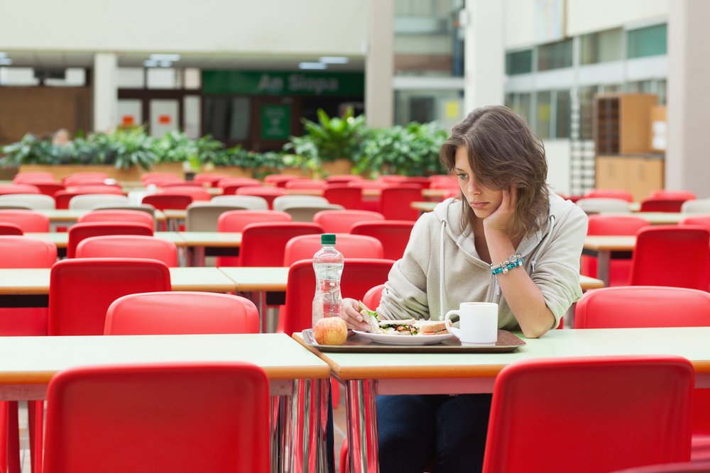 Alone and sad female student sitting in the cafeteria